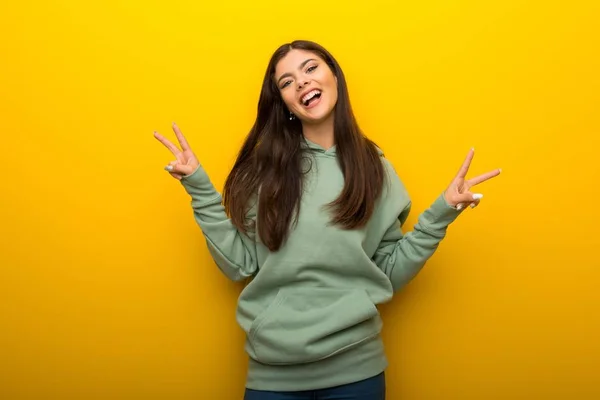 Genç Kız Ile Gülümseyen Iki Elini Zafer Işaretiyle Gösterilen Sarı — Stok fotoğraf
