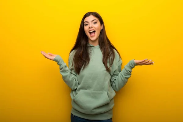 Chica Adolescente Con Sudadera Verde Sobre Fondo Amarillo Con Sorpresa —  Fotos de Stock