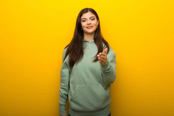 Tiener Meisje Met Groene Sweater Gele Achtergrond Schudden Handen Voor — Stockfoto