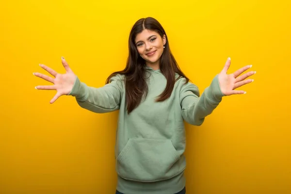 Chica Adolescente Con Sudadera Verde Sobre Fondo Amarillo Presentando Invitando —  Fotos de Stock