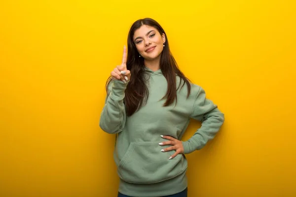 Tiener Meisje Met Groene Sweater Gele Achtergrond Weergeven Een Vinger — Stockfoto