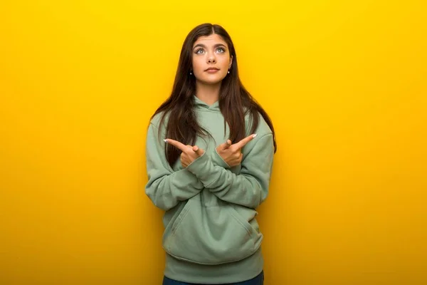 Teenagermädchen Mit Grünem Sweatshirt Auf Gelbem Hintergrund Das Auf Die — Stockfoto
