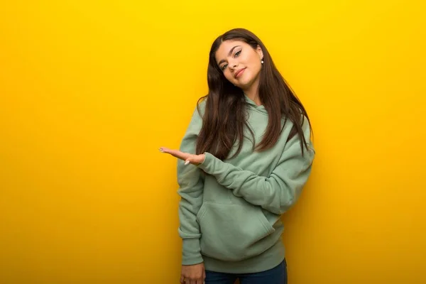 Tiener Meisje Met Groene Sweater Gele Achtergrond Een Idee Presenteren — Stockfoto