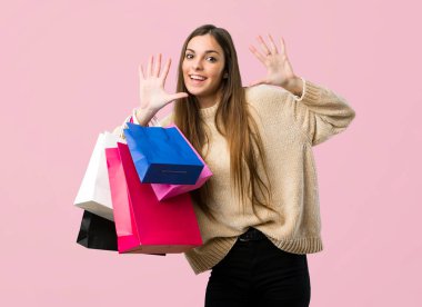 Alışveriş torbaları on ile izole pembe bir arka plan üzerinde parmak sayma ile genç kız