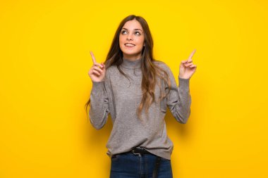 Harika bir fikir işaret parmağı ile işaret sarı duvarın üzerinden genç kadın
