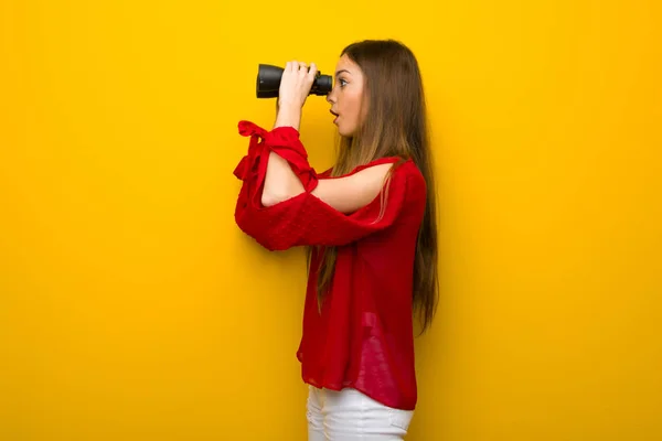 Mladá Dívka Červenými Šaty Žluté Zdi Dálce Při Pohledu Dalekohledem — Stock fotografie