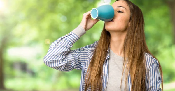 アウトドアでコーヒーのホットカップを保持しているストライプのシャツを持つ少女 — ストック写真