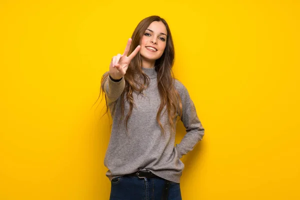Young Woman Yellow Wall Smiling Showing Victory Sign — Stock Photo, Image