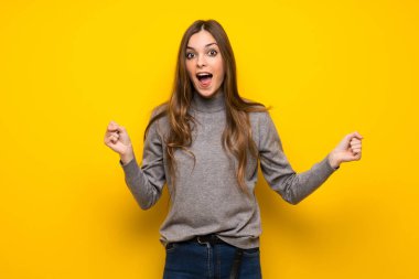 Sürpriz ve şok yüz ifadesi ile sarı duvarın üzerinden genç kadın