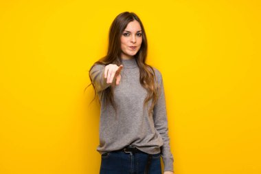 Genç kadın sarı duvarın üzerinden parmak seni kendinden emin bir ifadesiyle işaret