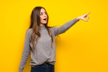 Sarı duvar uzağa işaret üzerinde genç kadın