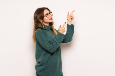 Genç kız ve işaret parmağı ile işaret yukarıya bakıyor beyaz duvar üzerinde