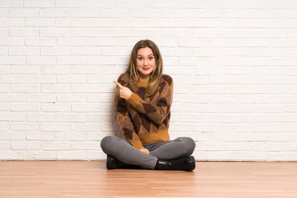 Adolescente Sentada Chão Apontando Para Lado Para Apresentar Produto — Fotografia de Stock