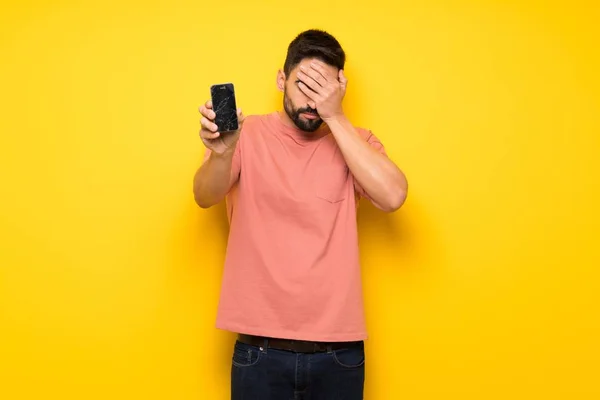 Hombre Guapo Sobre Pared Amarilla Con Problemas Para Sostener Teléfono —  Fotos de Stock