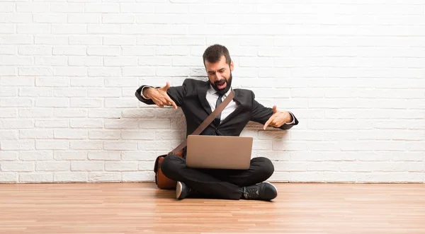 Biznesmen Swojego Laptopa Siedząc Podłodze Wskazując Palcem Kogoś Śmiech — Zdjęcie stockowe