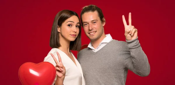 Paar Valentinstag Lächelnd Und Mit Beiden Händen Auf Rotem Hintergrund — Stockfoto
