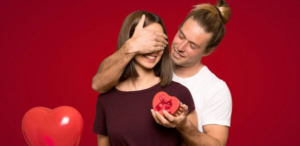 Pareja San Valentín Sosteniendo Caja Regalo Sobre Fondo Rojo —  Fotos de Stock