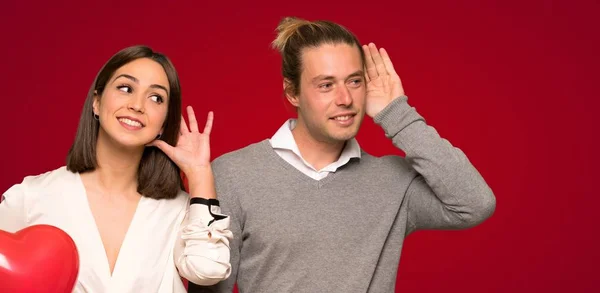 Couple Valentine Day Listening Something Putting Hand Ear Red Background — Stock Photo, Image