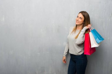 Dokulu duvar alışveriş torbaları bir sürü tutan genç kadın