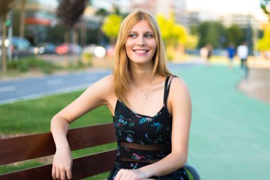 Genç ve güzel genç kız tatlı bir ifadeyle gülümseyen bir parkta