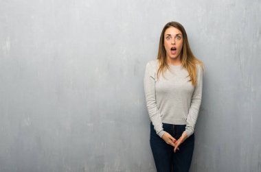 Sürpriz ve şok yüz ifadesi ile dokulu duvar genç kadın