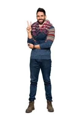 Gülümseyen ve zafer gösterilen hippi insanın tam uzunlukta atış izole beyaz arka plan üzerinde oturum