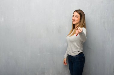 Genç kadın dokulu duvar üzerinde parmak seni kendinden emin bir ifadesiyle işaret