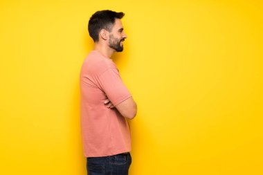 Lateral pozisyonda sarı duvarın üzerinden yakışıklı adam