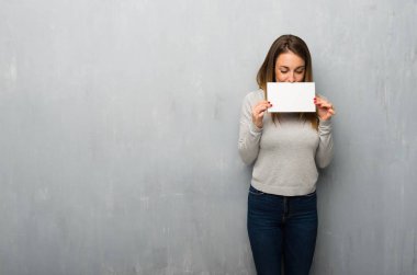 Genç kadın için bir afiş tutarak dokulu duvar eklemek bir kavram