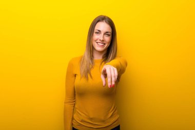 Genç kadın sarı arka plan üzerinde parmak seni kendinden emin bir ifadesiyle işaret