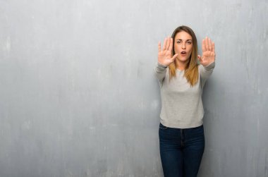 Genç kadın dokulu duvar dur jest yapmak için bir görüş ile hayal kırıklığına