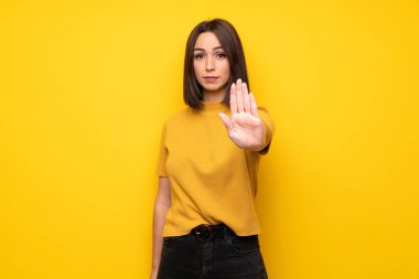 Genç kadın yanlış düşünüyor bir durum inkar durdurmak jest yaparak sarı duvarın üzerinden