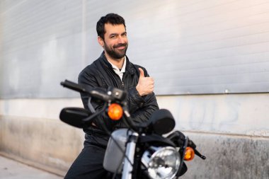 Başparmak ile bir motosiklet üzerinde genç adam