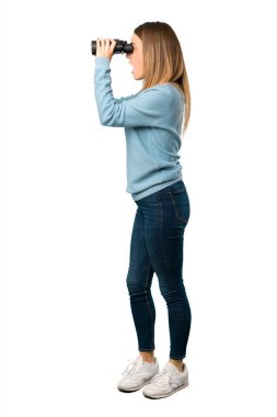 Mavi gömlek ve beyaz arka plan üzerinde dürbün ile mesafe seyir ile sarışın kadının tam vücut