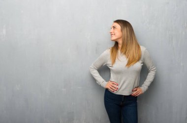 Genç kadın kalça, silah ile poz ve gülerek dokulu duvar