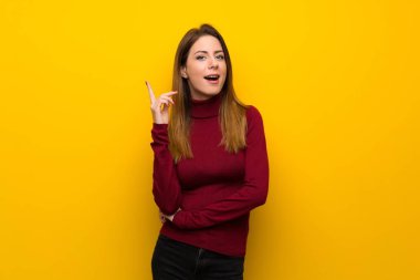 Balıkçı yaka parmak işaret bir fikir düşünce sarı duvarın üzerinden kadınla