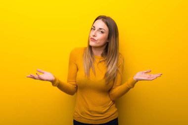 Sarı arka plan eller ve omuzlar yetiştirme süre şüpheleri üzerinde genç kadın