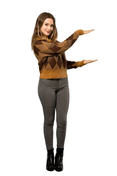 分離の白い背景の上に広告を挿入する Copyspace を保持している茶色のセーターとティーンエイ ジャーの女の子のフルレングス ショット — ストック写真