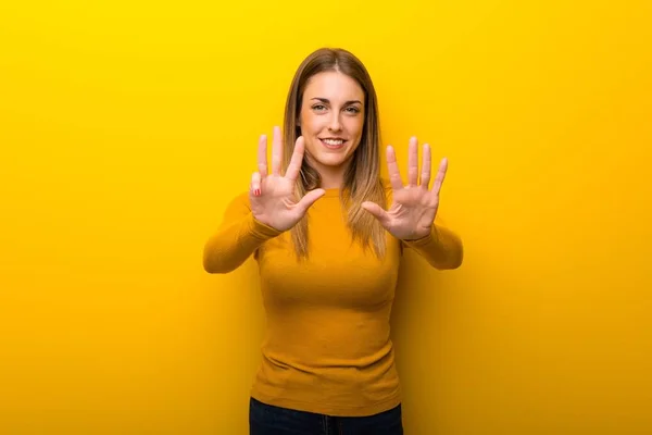 Mujer Joven Sobre Fondo Amarillo Contando Nueve Con Los Dedos —  Fotos de Stock
