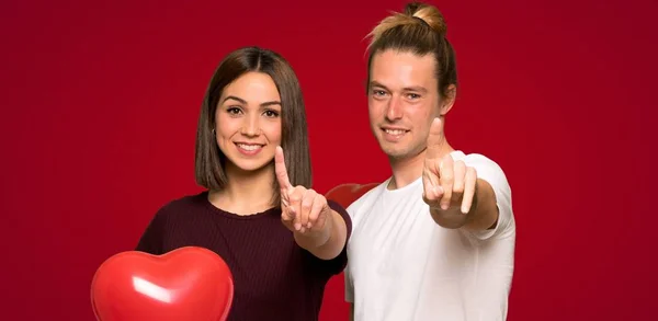 Paar Valentinstag Zeigt Und Hebt Einen Finger Über Roten Hintergrund — Stockfoto