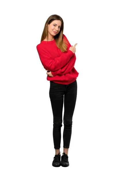 一个穿着红色毛衣的年轻女子的全长照片 指着孤立的白色背景 — 图库照片