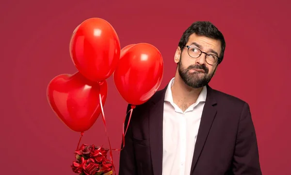 Man in valentine day with confuse face expression while bites lip over red background