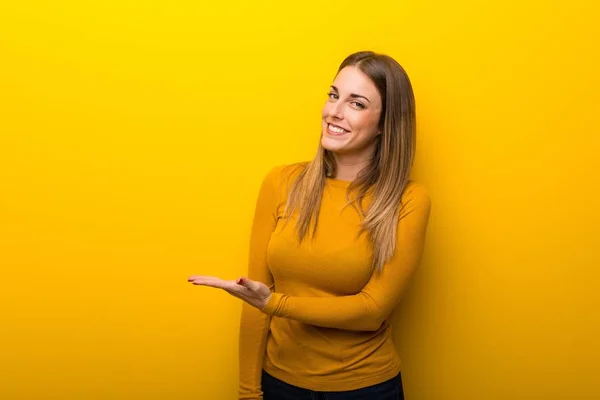 Jovem Mulher Fundo Amarelo Apresentando Uma Ideia Enquanto Olha Sorrindo — Fotografia de Stock