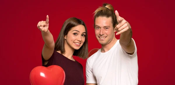 Paar Valentinstag Zeigt Mit Selbstbewusstem Gesichtsausdruck Auf Roten Hintergrund — Stockfoto