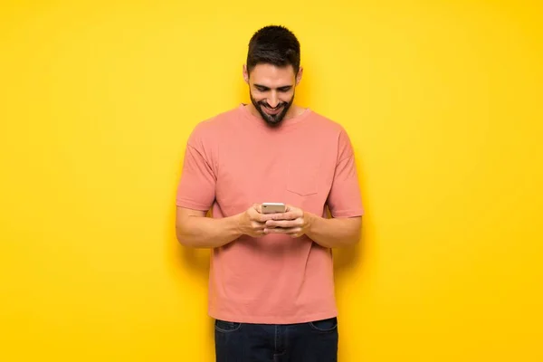 Hombre Guapo Sobre Pared Amarilla Enviando Mensaje Con Móvil —  Fotos de Stock