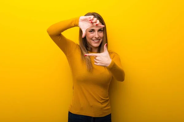 黄色背景上的年轻女子聚焦脸 框架符号 — 图库照片