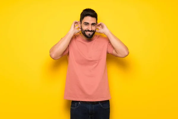 Hombre Guapo Sobre Pared Amarilla Cubriendo Orejas Con Las Manos — Foto de Stock