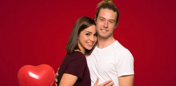 バレンタイン日ハグの赤い背景の上のカップル — ストック写真