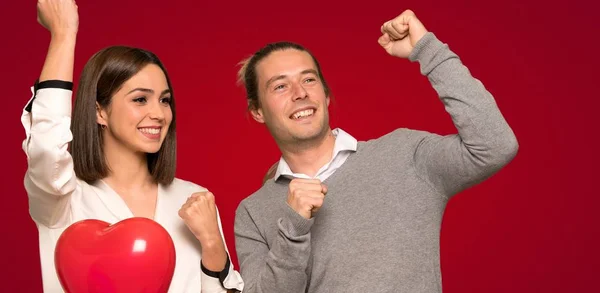 Couple in valentine day celebrating a victory over red background