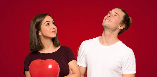 Para Walentynki Patrząc Jednocześnie Uśmiechając Się Czerwonym Tle — Zdjęcie stockowe